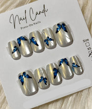 Load image into Gallery viewer, Silver press-on nails with blue bow designs on a white card with 'Nail Candi' branding.

