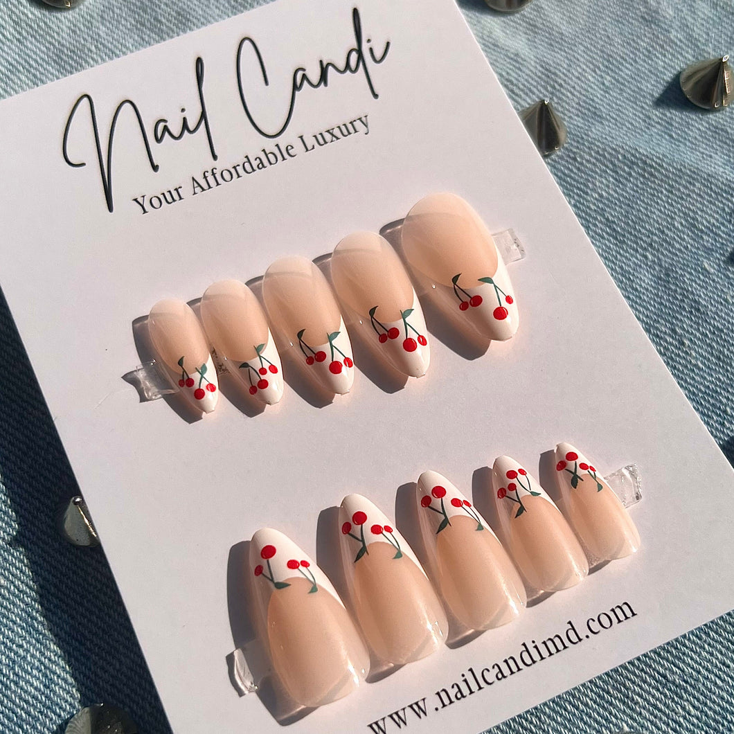Medium length almond shape nails with white french tip and red cherry designs